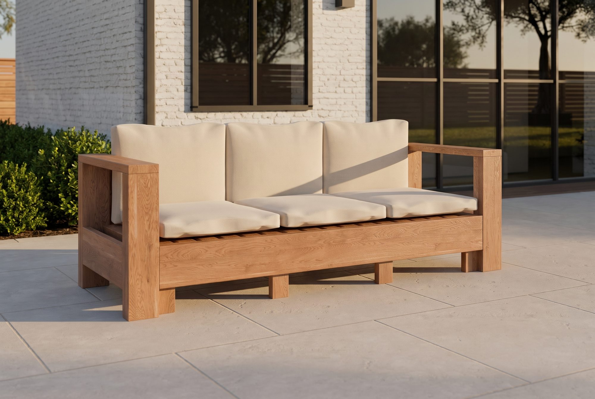 The Frame Sofa in honey-oiled cedar with linen cushions on a backyard patio